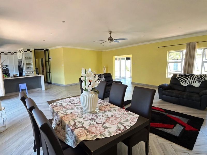 Spacious open-plan living and dining area featuring tiled flooring, recessed lighting, a ceiling fan, and a functional kitchen with built-in cabinetry.