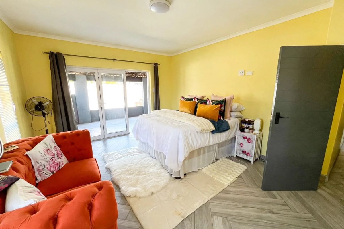 Spacious bedroom featuring herringbone tile flooring and large sliding glass doors that provide direct access to an outdoor patio area.