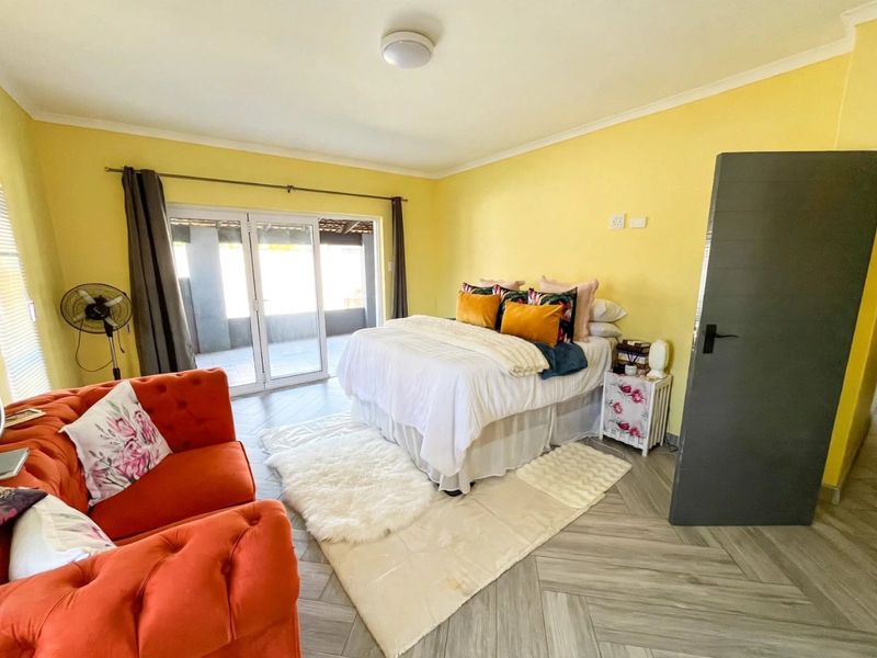 Spacious bedroom featuring herringbone tile flooring and large sliding glass doors that provide direct access to an outdoor patio area.