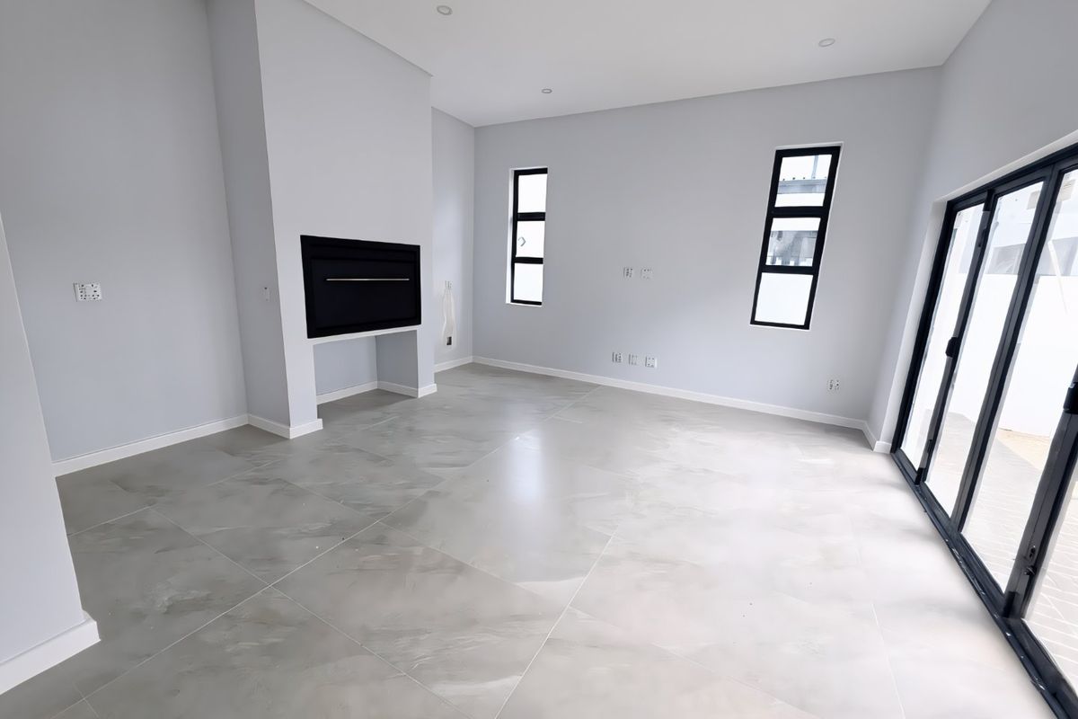 A bright, modern, and spacious living area featuring large format floor tiles, a built-in fireplace, and expansive sliding doors leading to the outdoors.