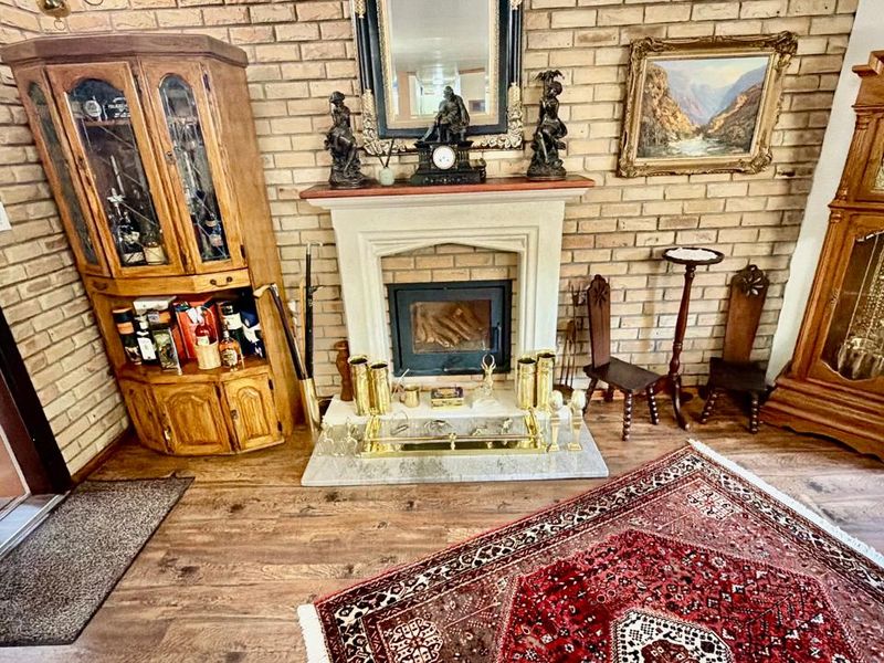 A cozy living room featuring an exposed brick wall, a central fireplace with a stone hearth, and wood-look flooring.
