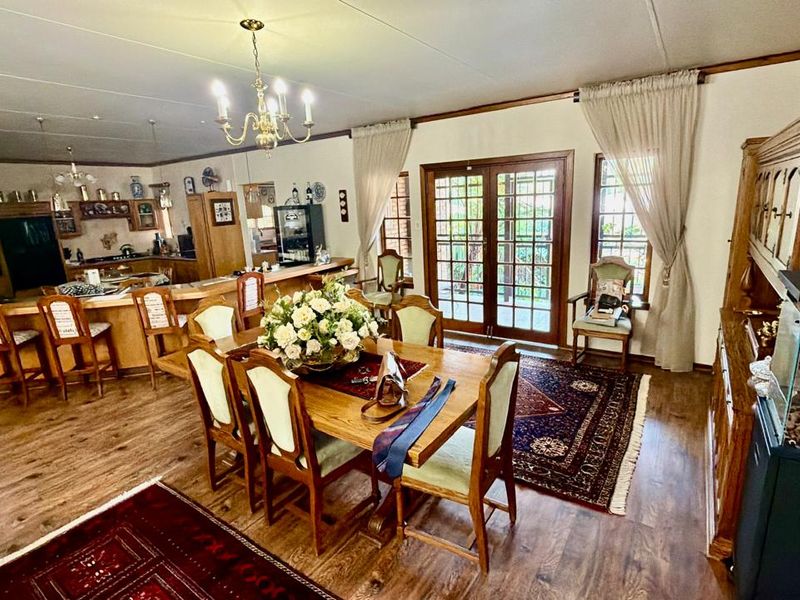 Spacious open-plan living and dining area featuring timber flooring, a breakfast bar, and direct access to the patio through classic french doors.