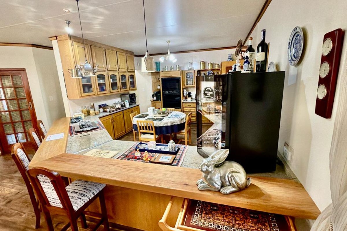 A traditional kitchen featuring extensive wooden cabinetry, a built-in oven, and a functional breakfast bar area with pendant lighting.