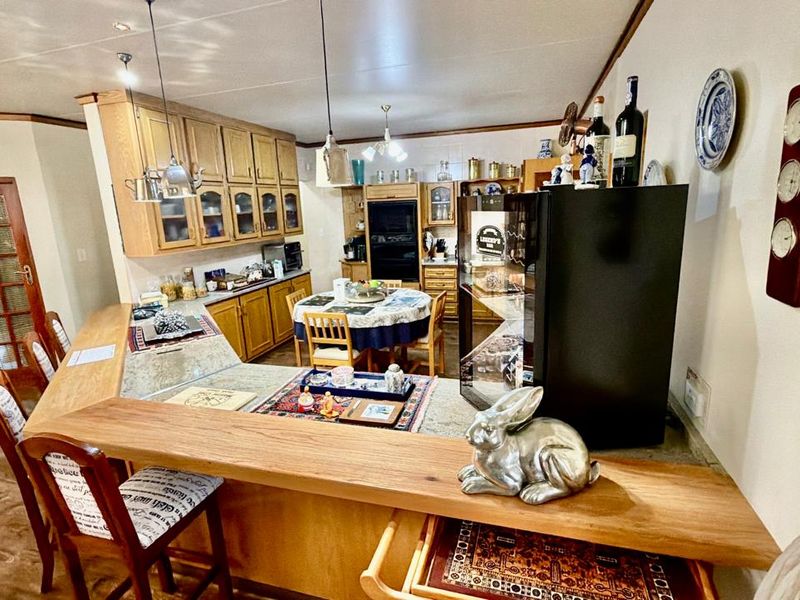 A traditional kitchen featuring extensive wooden cabinetry, a built-in oven, and a functional breakfast bar area with pendant lighting.
