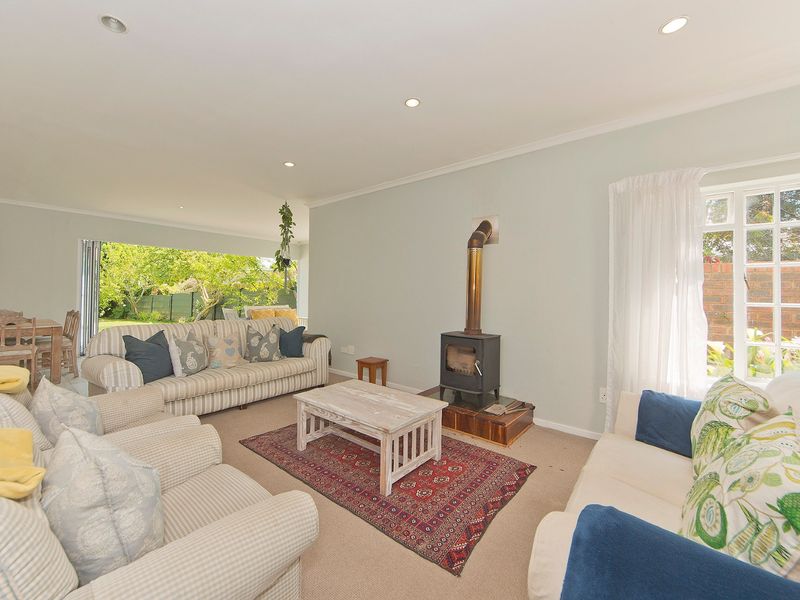 Spacious open-plan living area featuring a cozy wood-burning fireplace, recessed lighting, and large stacking doors that open to the garden.