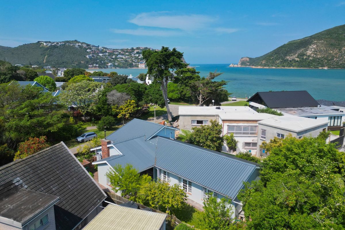 Aerial view of the property showcasing the metal roof, brick chimney, and surrounding coastal landscape with proximity to the lagoon.