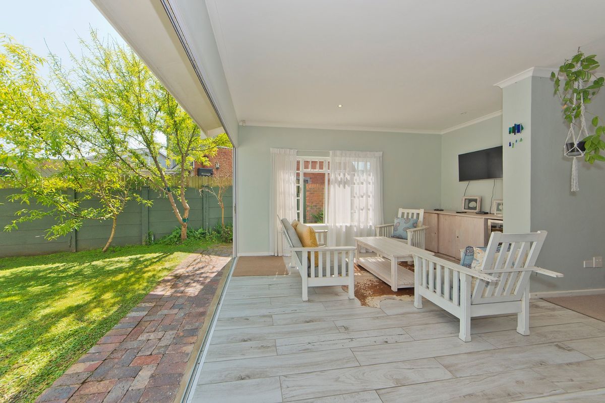Bright living room featuring wood-look tile flooring, recessed lighting, and large sliding glass doors that open directly onto the garden patio.