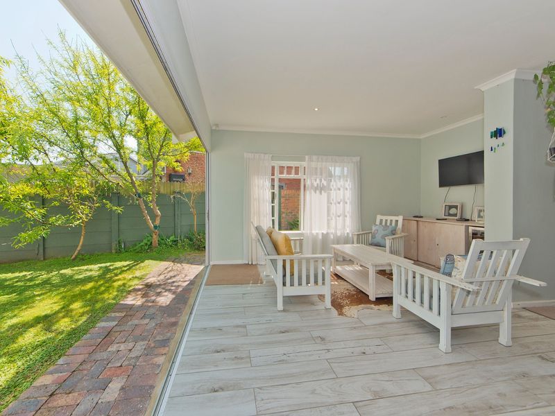 Bright living room featuring wood-look tile flooring, recessed lighting, and large sliding glass doors that open directly onto the garden patio.