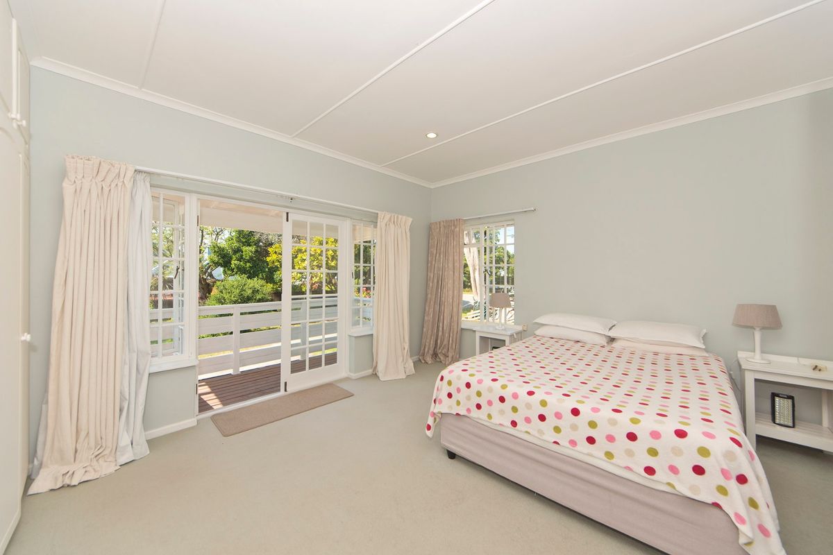 Spacious bedroom featuring neutral carpeting, built-in cupboards, and direct access to an outdoor balcony through classic french doors.
