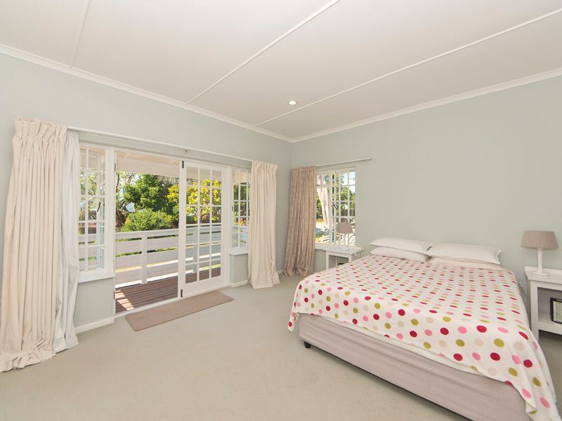 Spacious bedroom featuring neutral carpeting, built-in cupboards, and direct access to an outdoor balcony through classic french doors.