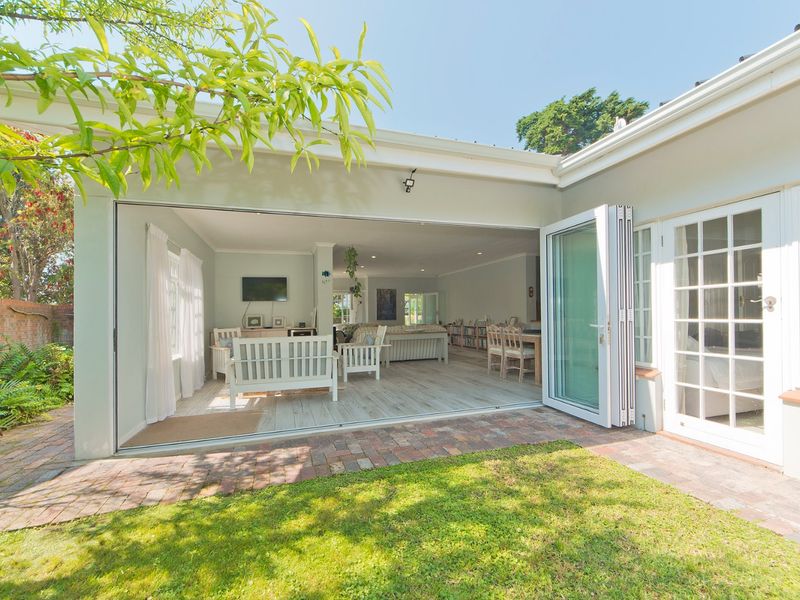 A seamless indoor-outdoor living space featuring wide bi-fold doors opening onto a brick-paved patio and garden area.