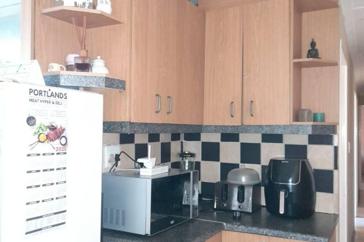 A functional kitchen featuring light wood-tone cabinetry, dark granite-look countertops, and a distinctive black and white checkered tile backsplash.