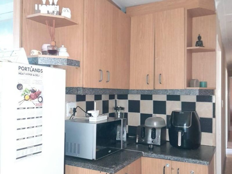 A functional kitchen featuring light wood-tone cabinetry, dark granite-look countertops, and a distinctive black and white checkered tile backsplash.