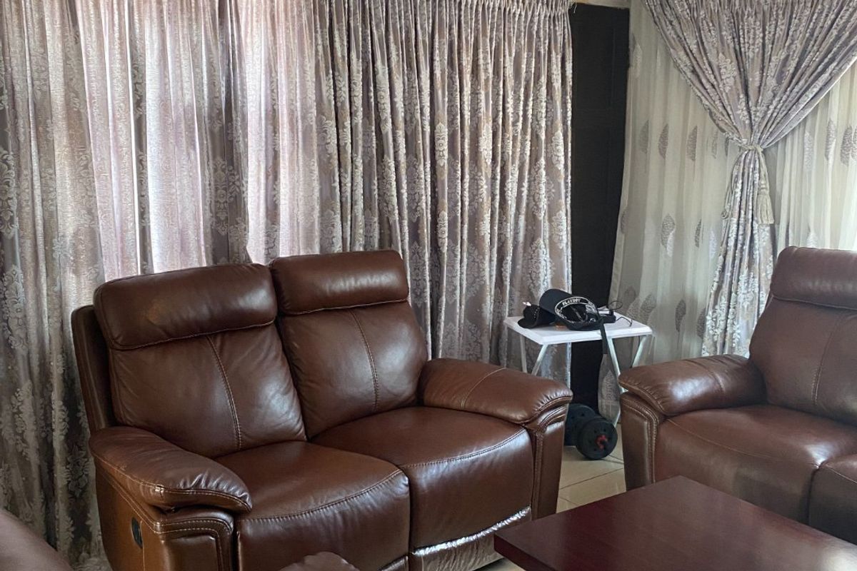 A living room area featuring tiled flooring and decorative ceiling cornicing, currently showing signs of wear including visible ceiling cracks.