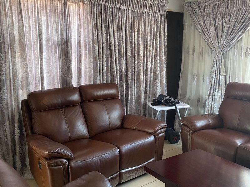 A living room area featuring tiled flooring and decorative ceiling cornicing, currently showing signs of wear including visible ceiling cracks.