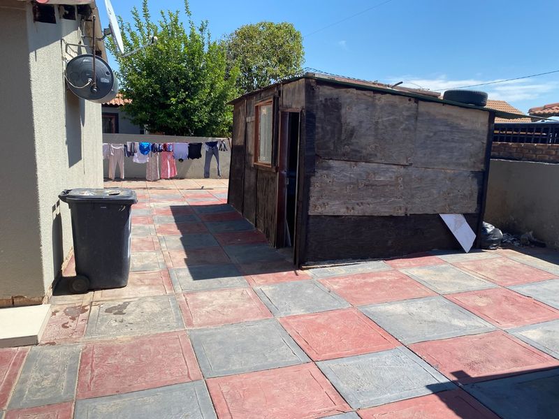 Rear exterior area featuring a paved patio and a weathered storage shed structure.