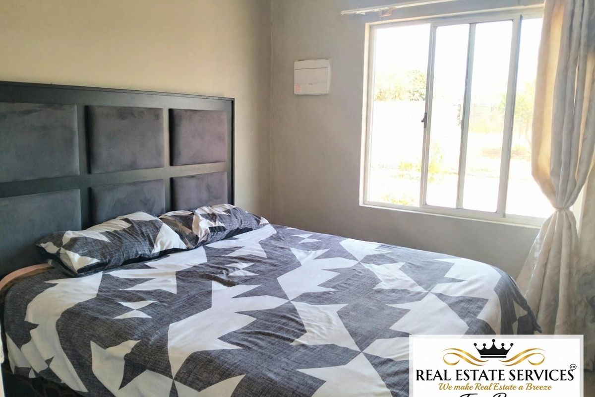 A functional bedroom featuring a sliding window and neutral wall finishes, providing a comfortable space for rest.