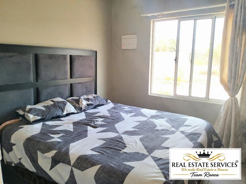 A functional bedroom featuring a sliding window and neutral wall finishes, providing a comfortable space for rest.