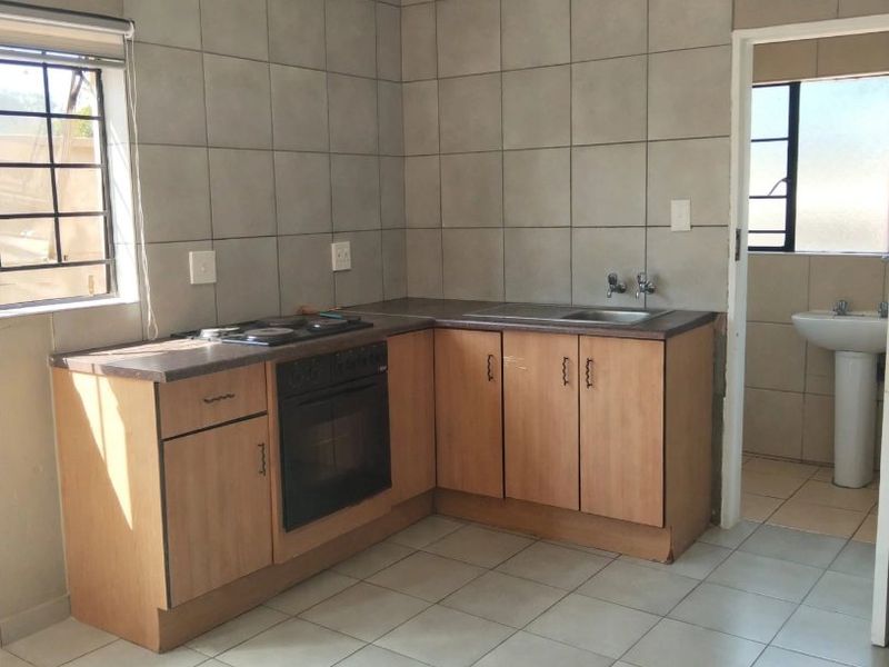 A functional kitchen featuring built-in cabinetry, a hob, an oven, and tiled finishes, offering a clean space ready for modernization.