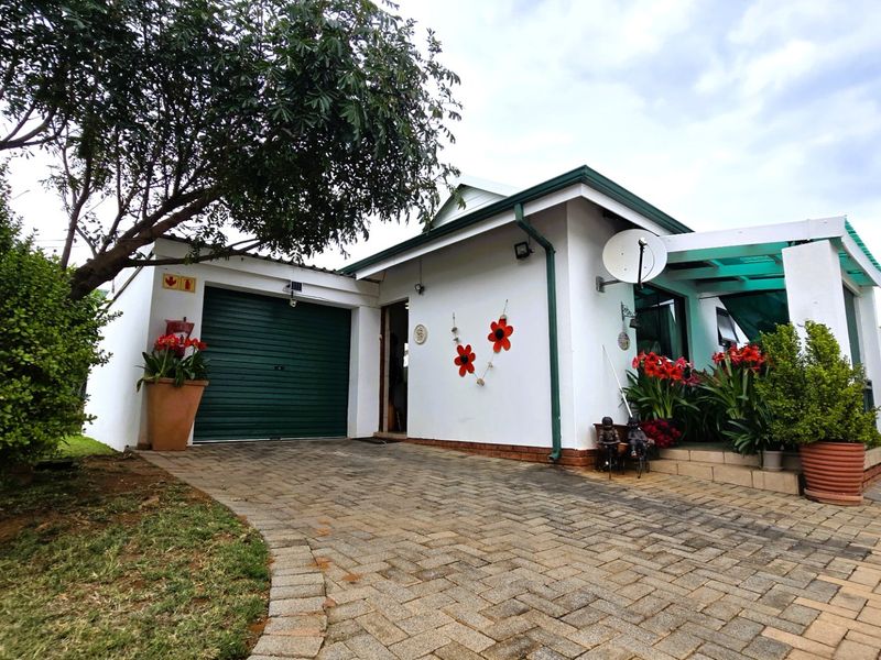 Front view of a townhouse featuring a paved driveway, single garage with a roller shutter door, and a covered patio entrance.