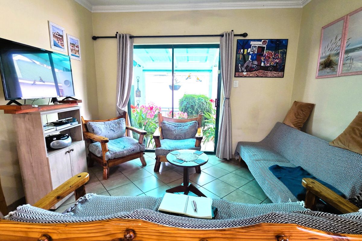 A cozy living room featuring ceramic floor tiles and a large sliding glass door that provides direct access to the outdoor patio area.