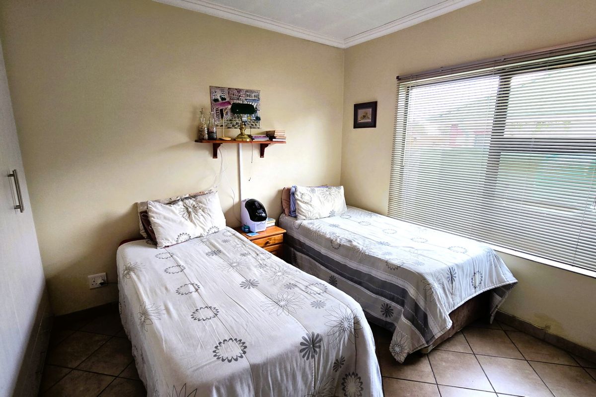 A bedroom featuring tiled flooring, built-in wardrobe storage, and venetian blinds, with visible signs of moisture damage on the lower wall section.