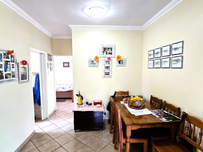 A functional dining area featuring ceramic floor tiles, decorative ceiling cornices, and neutral wall finishes, providing a practical space for family meals.