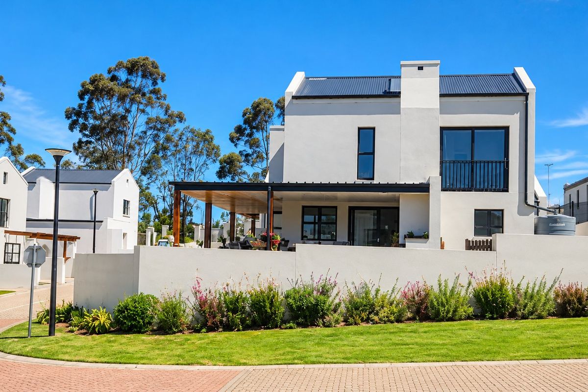 A modern double-story residential home featuring a covered patio, balcony, and clean architectural lines, set within a well-maintained estate environment.