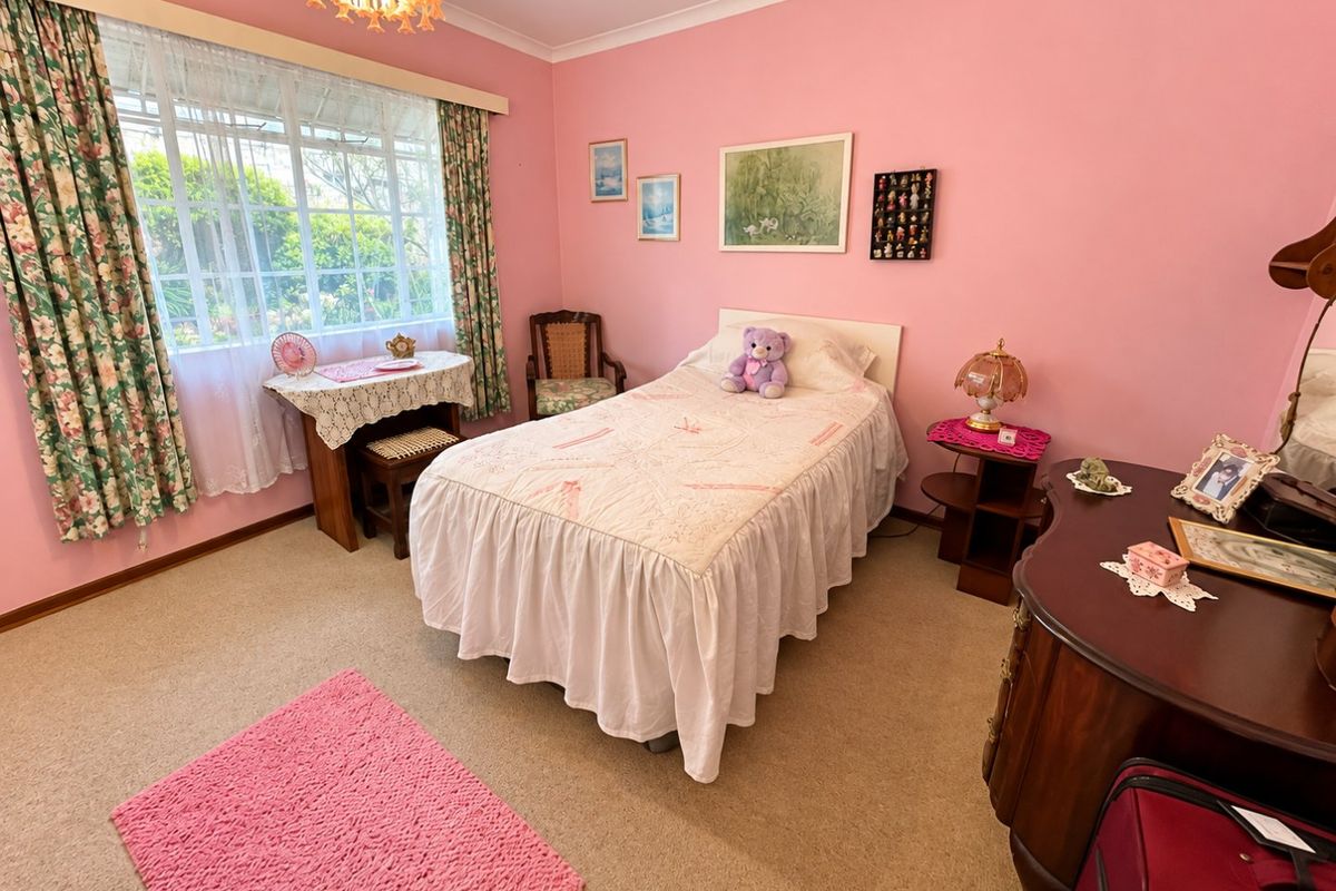 A well-maintained bedroom featuring carpeted flooring, a large window providing natural light, and classic cove cornice detailing.