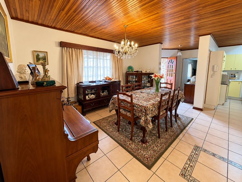 Open plan dining area featuring a warm timber ceiling, ceramic tiled flooring with decorative inlay, and direct access to the adjoining kitchen.