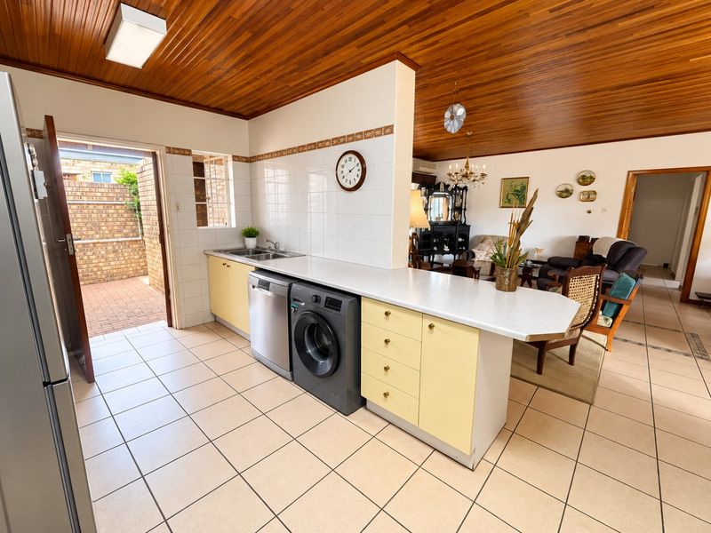 Open plan kitchen and living area featuring timber ceilings, tiled flooring, and direct access to an outdoor patio area.