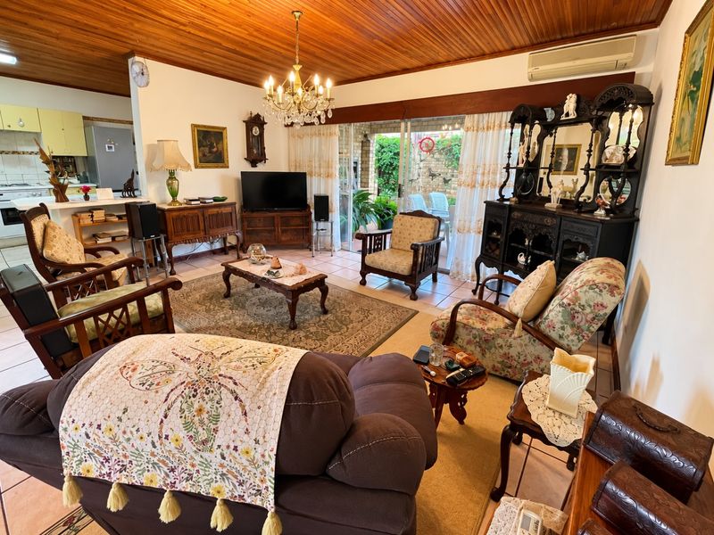 Spacious open-plan living area featuring a timber ceiling, tiled floors, and direct access to the patio, with an adjoining kitchen and breakfast bar.