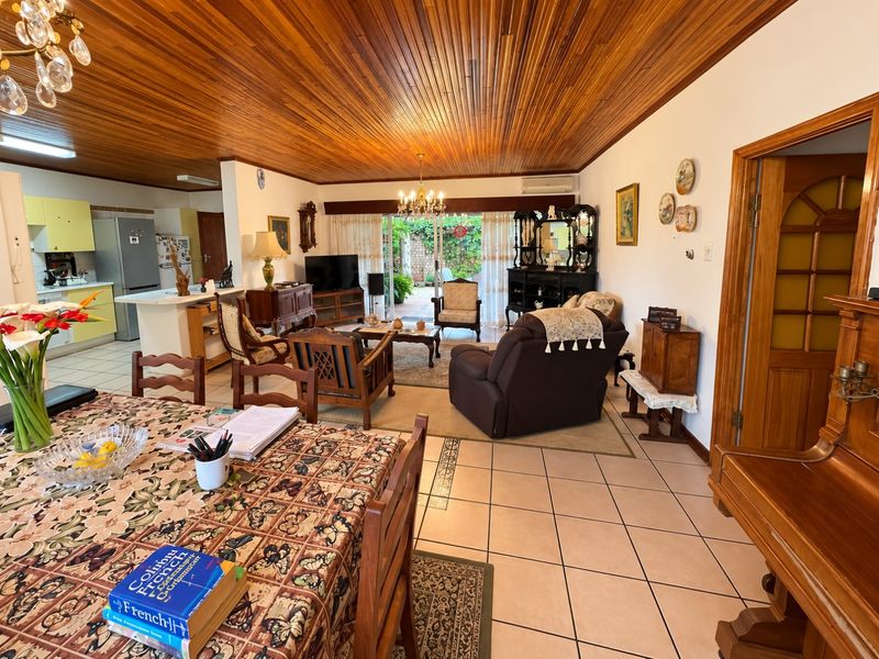 Spacious open-plan living and dining area featuring a distinctive timber ceiling, ceramic tiled flooring, and direct access to the rear patio through sliding doors.