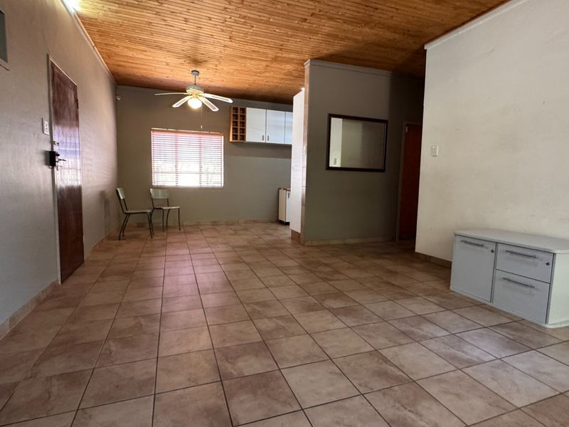 Spacious open-plan living area featuring tiled flooring, a timber ceiling, and built-in cabinetry, offering a versatile layout for various living arrangements.