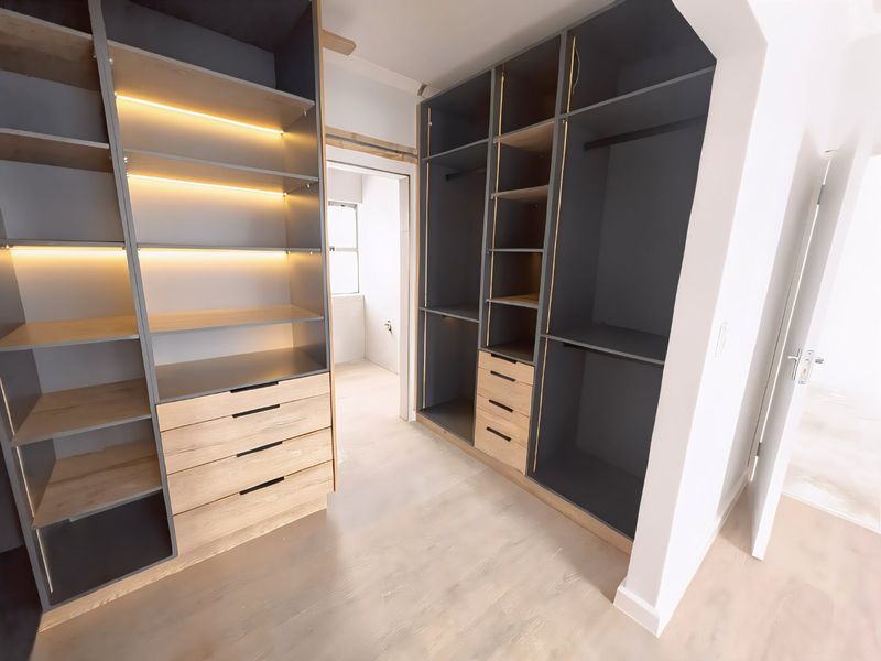 A modern walk-in closet or dressing area featuring custom built-in cabinetry with integrated LED lighting and light wood-tone finishes.