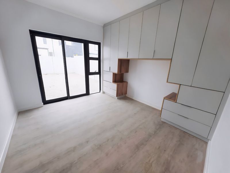 Modern bedroom featuring extensive built-in cabinetry with integrated shelving and large sliding glass doors providing access to the exterior.