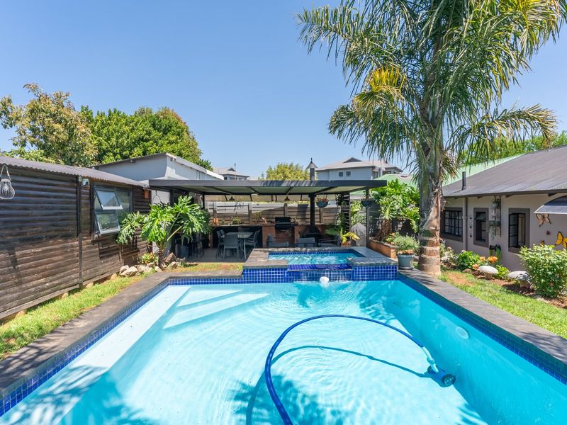 Outdoor entertainment area featuring a swimming pool with an integrated raised spa and a covered patio with a built-in braai.