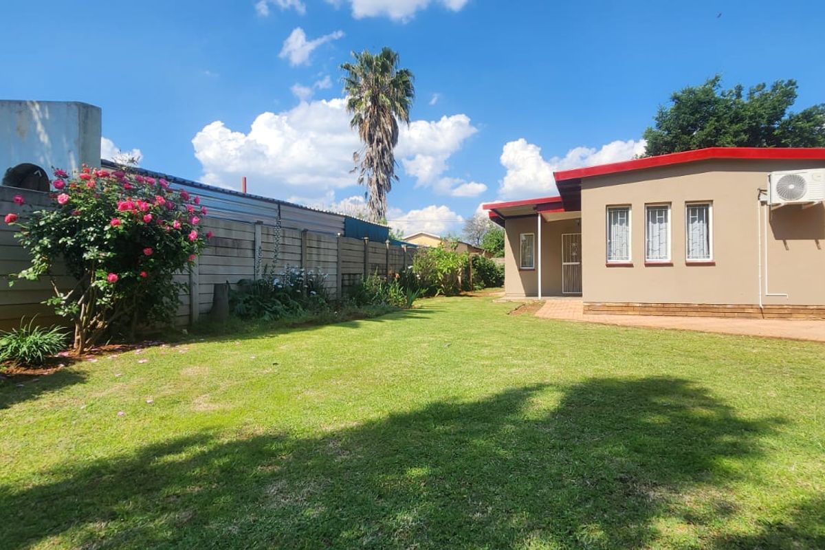 A well-maintained rear garden featuring a spacious lawn, paved walkway, and secure boundary wall, providing a private outdoor space.