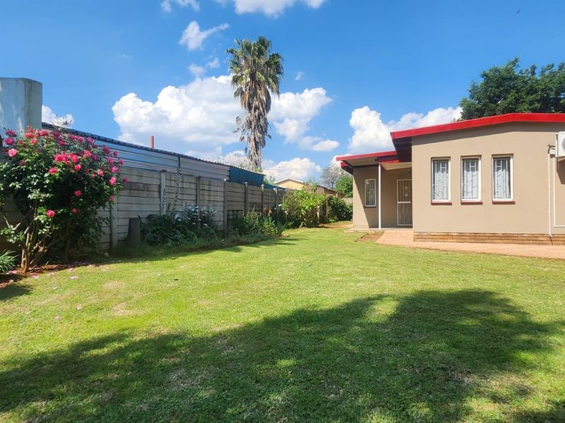 A well-maintained rear garden featuring a spacious lawn, paved walkway, and secure boundary wall, providing a private outdoor space.