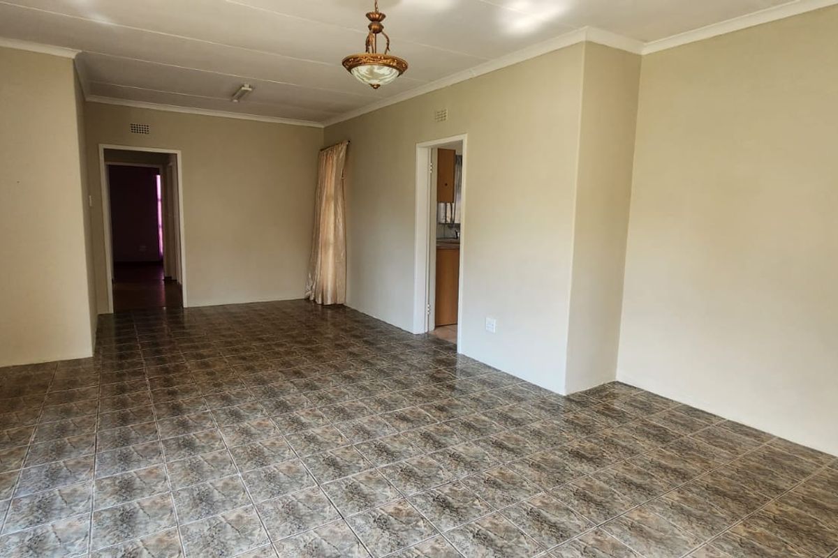 A spacious, empty living area featuring neutral wall tones and durable tiled flooring, providing a versatile blank canvas for interior design.