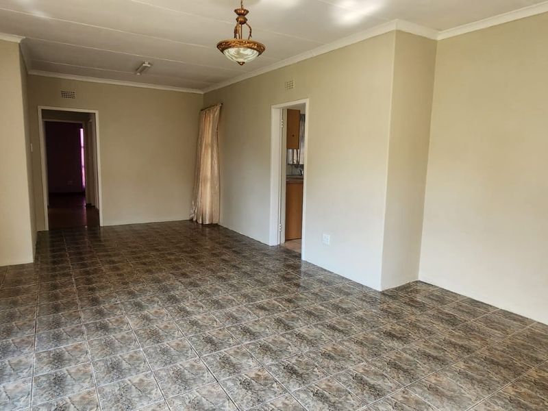 A spacious, empty living area featuring neutral wall tones and durable tiled flooring, providing a versatile blank canvas for interior design.