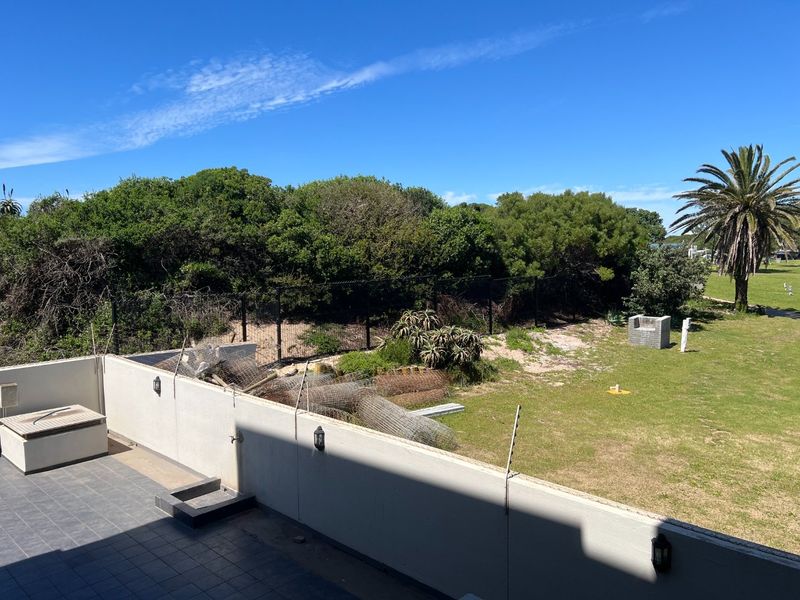 A tiled balcony overlooking a rear garden area with perimeter walling, electric fencing, and outdoor lighting fixtures.