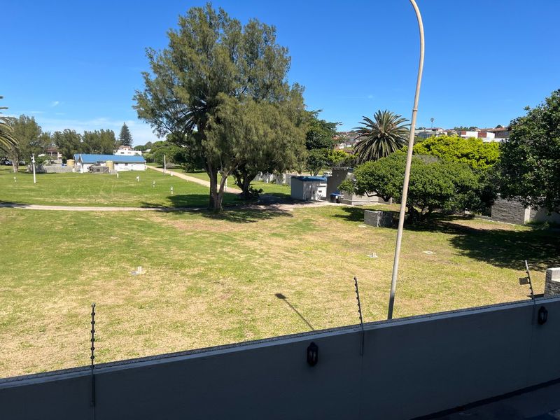 Elevated view overlooking a large communal green space with mature trees and surrounding residential infrastructure.