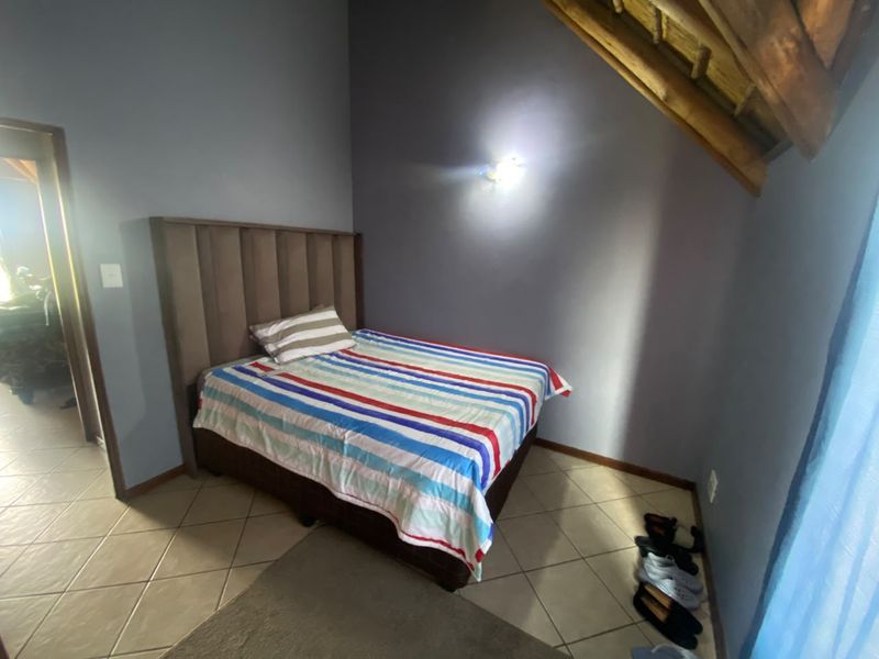 A bedroom featuring tiled flooring and exposed timber rafters, creating a cozy atmosphere under the pitched roof.