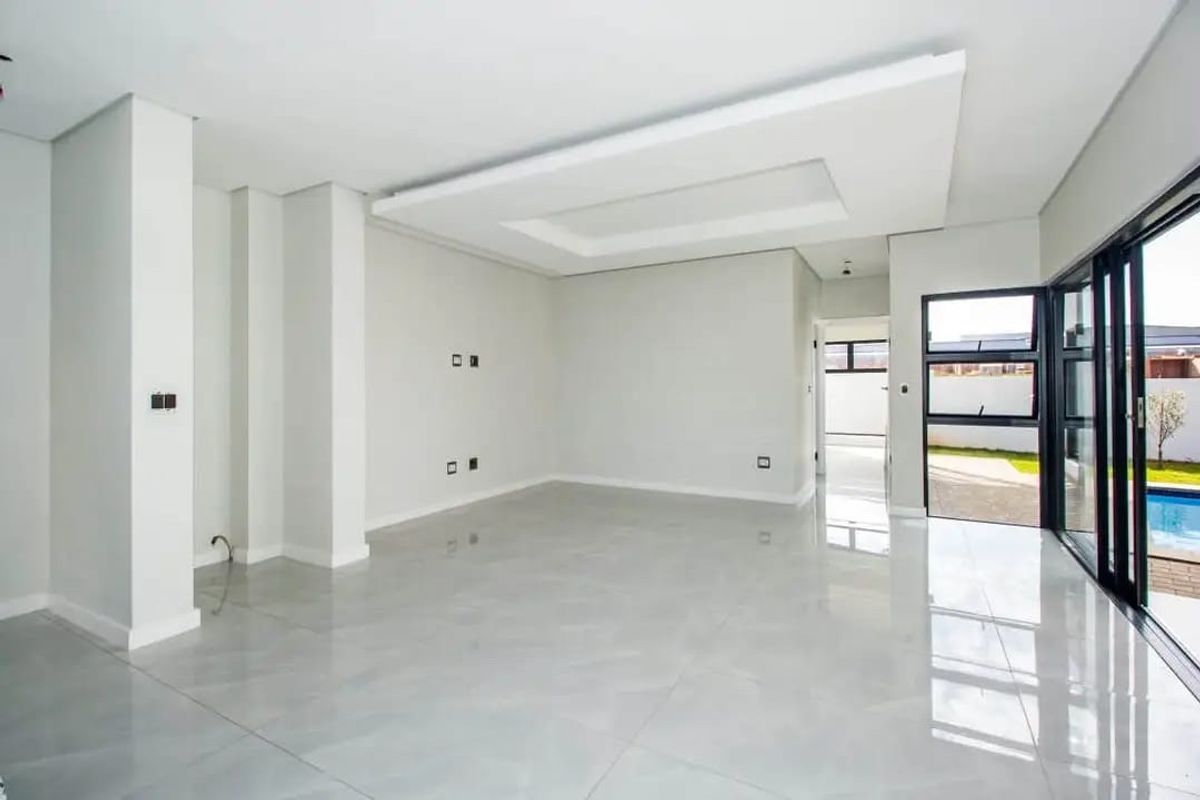 Spacious, modern living area featuring high-gloss porcelain tiles, a contemporary recessed ceiling design, and large sliding glass doors opening to the pool area.
