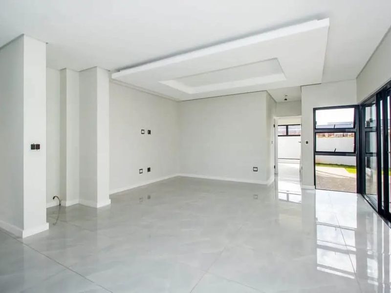 Spacious, modern living area featuring high-gloss porcelain tiles, a contemporary recessed ceiling design, and large sliding glass doors opening to the pool area.