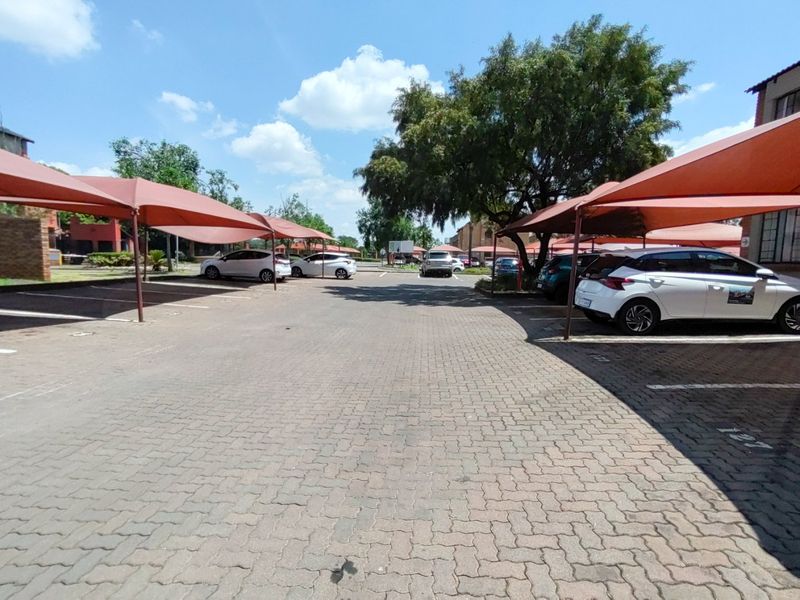 An outdoor parking area featuring paved ground and multiple shade cloth carports for vehicle protection within the apartment complex.