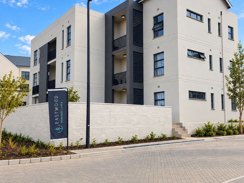 Modern multi-story apartment building exterior featuring clean architectural lines, private balconies, and a well-maintained paved driveway and landscaped surroundings.