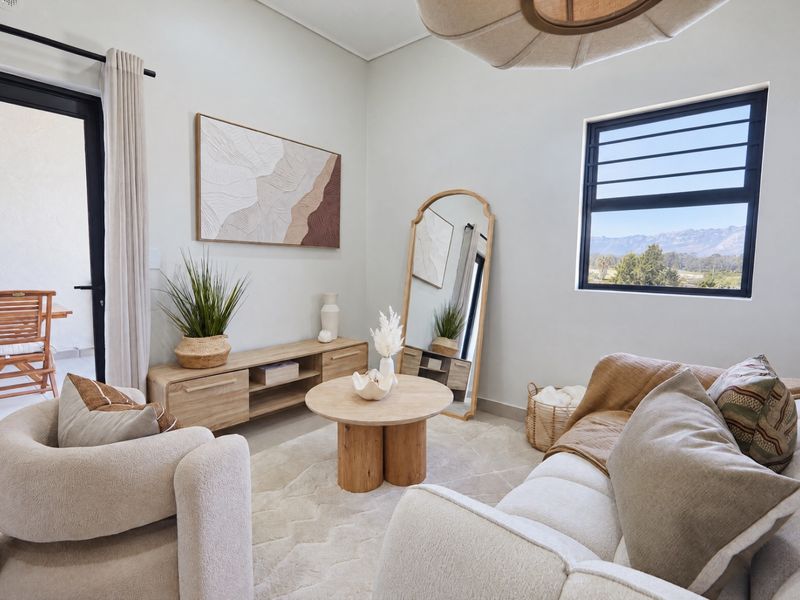 A bright and well-maintained living room featuring neutral tones, modern black-framed windows, and direct access to an outdoor patio area.
