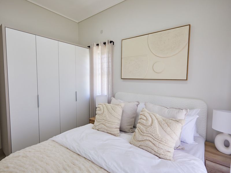 A well-maintained bedroom featuring a modern built-in wardrobe and neutral finishes, providing a clean and comfortable living space.